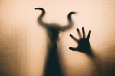 Karanlıkta, pencerenin arkasında boynuzları olan ürkütücü bir kafatası figürü