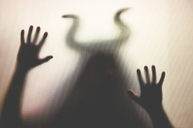 Karanlıkta, pencerenin arkasında boynuzları olan ürkütücü bir figür. Cadılar Bayramı geçmişi 