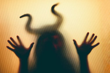 Karanlıkta, pencerenin arkasında boynuzları olan ürkütücü bir figür. Cadılar Bayramı geçmişi 