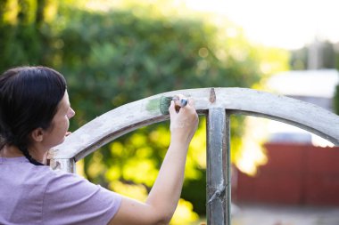 Orta yaşlı bir kadın ahşap mobilya boyuyor. Yepyeni renkli tebeşir boyasıyla eski moda ahşap mobilyaları yeniliyorum. Ev dekorasyonu yeniden biçimlendiriliyor