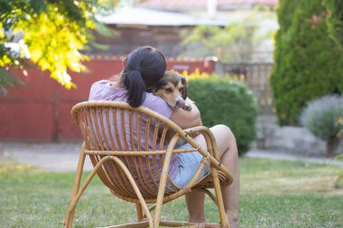 Sıradan, orta yaşlı bir kadın bahçede küçük kahverengi köpeğiyle eğleniyor. Hayvanlarla bağ kurma ve birlikte olmaktan keyif alma kavramı.