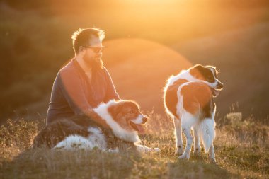 İnsan ve köpekleri güzel günbatımının tadını çıkarıyor.