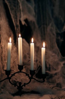 Dark Halloween background with candles and spider web. Spooky atmosphere, horror concept and holiday decoration.