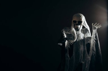 Creepy skeleton figure with skull in the dark. Wide banner format with copy space.