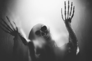 Creepy skeleton figure with skull behind matte glass. Halloween festival concept.Blurred picture