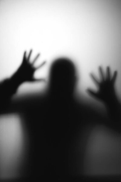 Horror, halloween background - Shadowy figure behind glass of a man