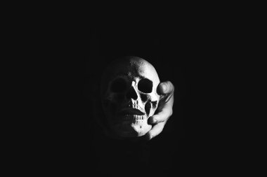 Siyah arka planda kafatası tutan eller, Cadılar Bayramı konsepti.