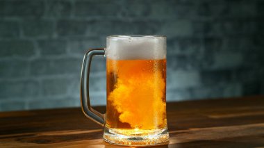 Freshly brewed beer in a pint on old wooden table, close-up