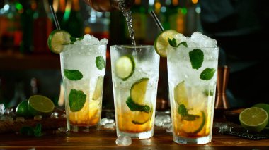 Fresh mojito cocktails on the bar, dark toned background