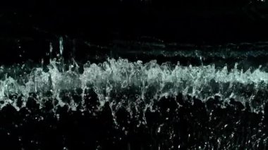 Siyah arka planda su sıçrayan süper yavaş çekim. 1000 FPS 'de yüksek hızlı sinematik kamera ile çekildi.