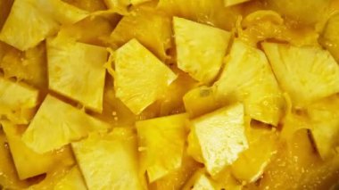 Meyve suyuna dökülen ananas dilimleri, makro shot. Makro arka plan. 1000 fps 'lik yüksek hızlı bir sinema kamerasında çekildi..