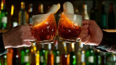 Barda bira bardakları için tezahürat yapan süper yavaş çekim. Yüksek hızlı sinema kamerası, 1000 fps. Arka planda şişe olan bir bar. Rampa hızı etkisi.