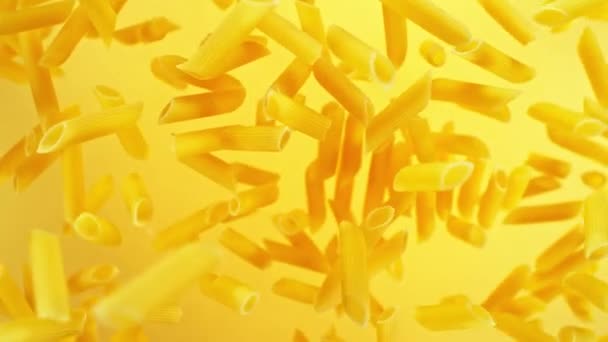 Super Slow Motion Flying Uncooked Italian Pasta Penne Golden Background — Video