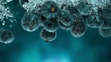 Mavi eğimli arka planda suya düşen taze yaban mersinlerinin süper yavaş çekimi. Yüksek hızlı sinema kamerası, 1000 fps..