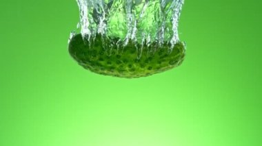 Yeşil eğimli arka planda suya taze salatalık düşmesi süper yavaş bir hareket. Yüksek hızlı sinema kamerası, 1000 fps..