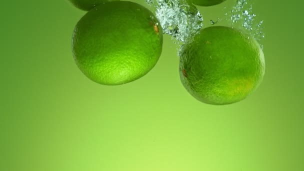 Super Slow Motion Falling Fresh Limes Water Green Gradient Background — Stock Video
