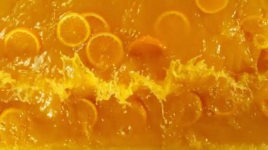 Meyve suyuna portakal dilimleri sıçrıyor, makro shot. Makro arka plan. 1000 fps 'lik yüksek hızlı bir sinema kamerasında çekildi..