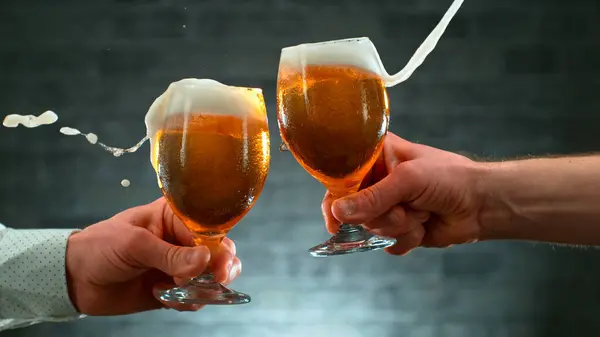 two glass of beer in hand. Beer glasses clinking in bar or pub