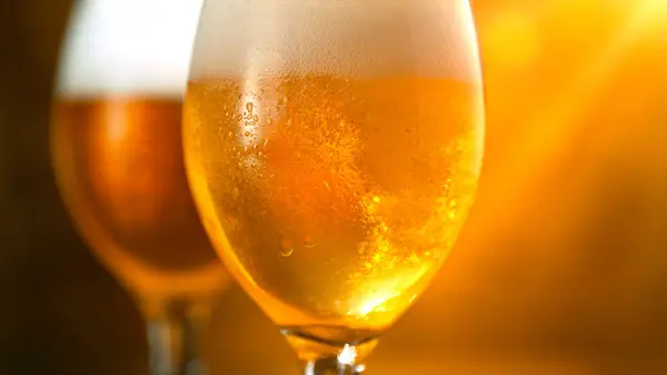 Freshly brewed beer in a pint on orange gradient background, close-up