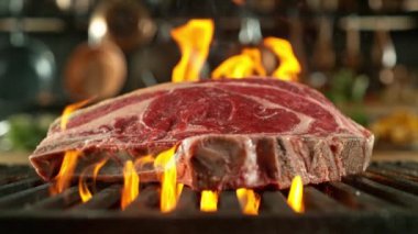 Yakından, kızgın demir ızgarada, çok yavaş çekimde, 1000 fps hızla sinematik kamerayla çekilen lezzetli çiğ biftek. Kamera hareketi.