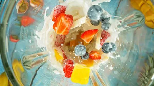 在搅拌机中搅拌草莓块与牛奶混合的冷冻运动 上镜头 图库图片