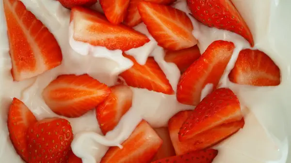 新鲜草莓掉进酸奶奶油里 从上往下看 图库照片