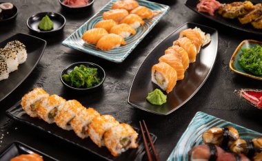 Geleneksel Japon mutfağının en iyi manzarası. Somon, ton balığı ve sebzeli suşi ruloları siyah taş masada servis edilir. Siyah taş üzerinde yemek çubuklarıyla Asya yemekleri. .