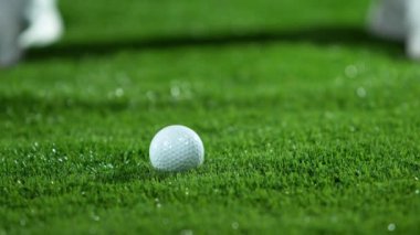 Golf sopası bir golf topuna çok yavaş bir şekilde 1000 fps hızla vuruyor. Sabah çiği damlaları ve çimen parçacıkları havaya yükselir. .