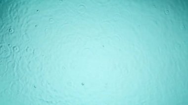 Açık mavi arkaplanda su damlalarının yavaş hareketi, yüksek hızlı sinematik kamerada 1000 FPS 'de çekiliyor.