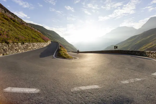 stock image Motorbiker riding in Italian Alps during sunrise, dramatic sky. Travel and freedom, outdoor activities