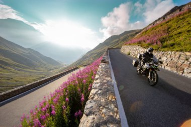 Gün doğumunda İtalyan Alplerinde motosikletli gezgin, dramatik bir gökyüzü. Seyahat ve özgürlük, açık hava aktiviteleri