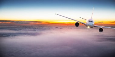 Günbatımında bulutların üzerinde uçan ticari uçaklar. Hızlı seyahat, tatil ve iş kavramı.