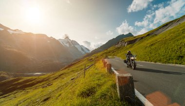 Gün doğumunda İtalyan Alplerinde motosikletli gezgin, dramatik bir gökyüzü. Seyahat ve özgürlük, açık hava aktiviteleri