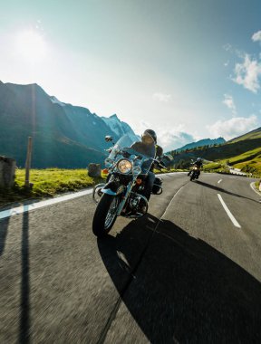 Gün doğumunda İtalyan Alplerinde motosikletli gezgin, dramatik bir gökyüzü. Seyahat ve özgürlük, açık hava aktiviteleri