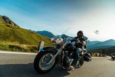 Gün doğumunda İtalyan Alplerinde motosikletli gezgin, dramatik bir gökyüzü. Seyahat ve özgürlük, açık hava aktiviteleri