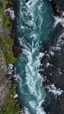 İzlanda 'da kayalık bir nehir kıyısında dalgalar yükseliyor.
