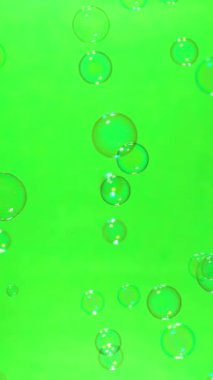 Yeşil ekran arka planında uçan sabun baloncuklarının süper yavaş çekimi, dikey yönelim, 1000 FPS