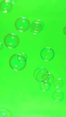 Yeşil ekran arka planında uçan sabun baloncuklarının süper yavaş çekimi, dikey yönelim, 1000 FPS
