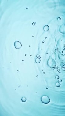 Açık mavi arkaplanda yavaş su sıçratma hareketi, yüksek hızlı sinematik kamerada 1000 FPS 'de çekilmiştir.