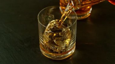 Super slow motion of pouring whisky into glass with speed motion. Filmed on high speed cinema camera, 1000 fps, placed on high speed cine bot. Bar with bottles on background.