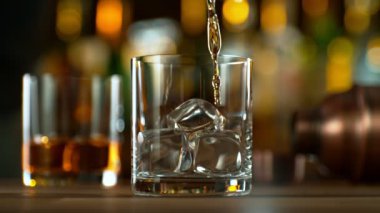 Viskiyi cama dökmenin çok yavaş bir yolu. Yüksek hızlı sinema kamerası, 1000 fps. Arka planda şişe olan bar.