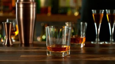 Super slow motion of pouring whisky into glass with speed motion. Filmed on high speed cinema camera, 1000 fps, placed on high speed cine bot. Bar with bottles on background.