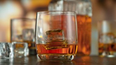 Super slow motion of pouring whisky into glass with speed motion. Filmed on high speed cinema camera, 1000 fps, placed on high speed cine bot. Bar with bottles on background.