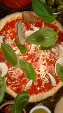 Çok yavaş çekimde pizza hamurunun üzerine çeşitli malzemeler dökülüyor.
