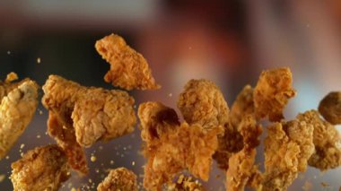 Süper yavaş çekimde uçan lezzetli tavuk parçaları ve kamera hareketi. Yüksek hızlı sinema kamerası, 1000 fps..