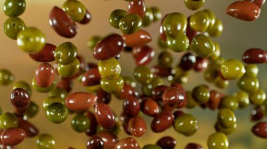 Uçan taze yeşil ve siyah zeytinlerin dondurucu hareketi, yakın plan.