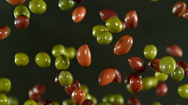 Uçan taze yeşil ve siyah zeytinlerin dondurucu hareketi, yakın plan.