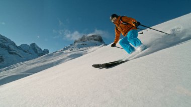 Skier riding in the scenic Alps mountains in fresh powder snow , beautiful sunny day clipart