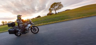 Günbatımında, sonbahar dağlarında, boş yolda motosiklet sürmek