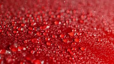 Kırmızı araba kaputuna yağmur damlaları yavaşça düşüyor, yakın plan.